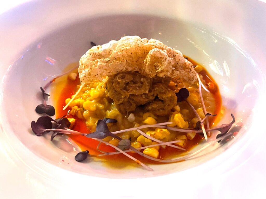 Organic Aborio Risotto, Pork Hash, Emulsified Pork Jus, Old Bay Seasoned Chicharron, Gently Broiled Corn, Chili Oil, and Micro Greens. Image by Emily Simpson.
