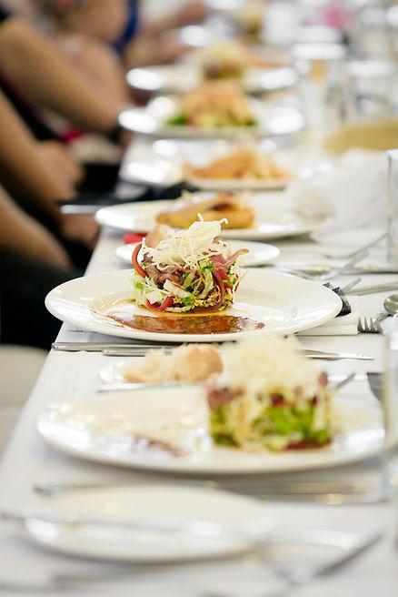 A table with elegantly plated salads, featuring greens and shredded cheese, set at a formal gathering. 