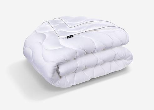 Folded white quilted comforter with black Bedgear label on a white studio background