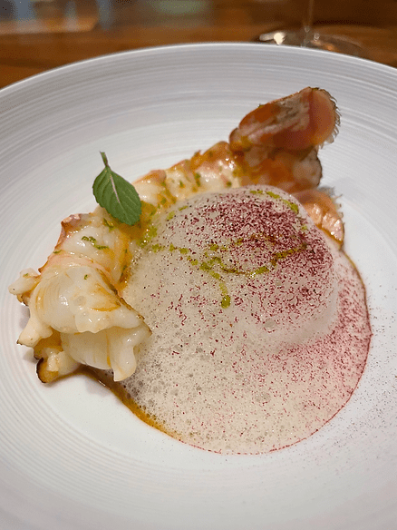 grilled Norway langoustine with nam prik chili paste, served alongside a sauce made from the langoustine heads with saté flavors, mango-purple curry chutney, and a pandan foam. 
