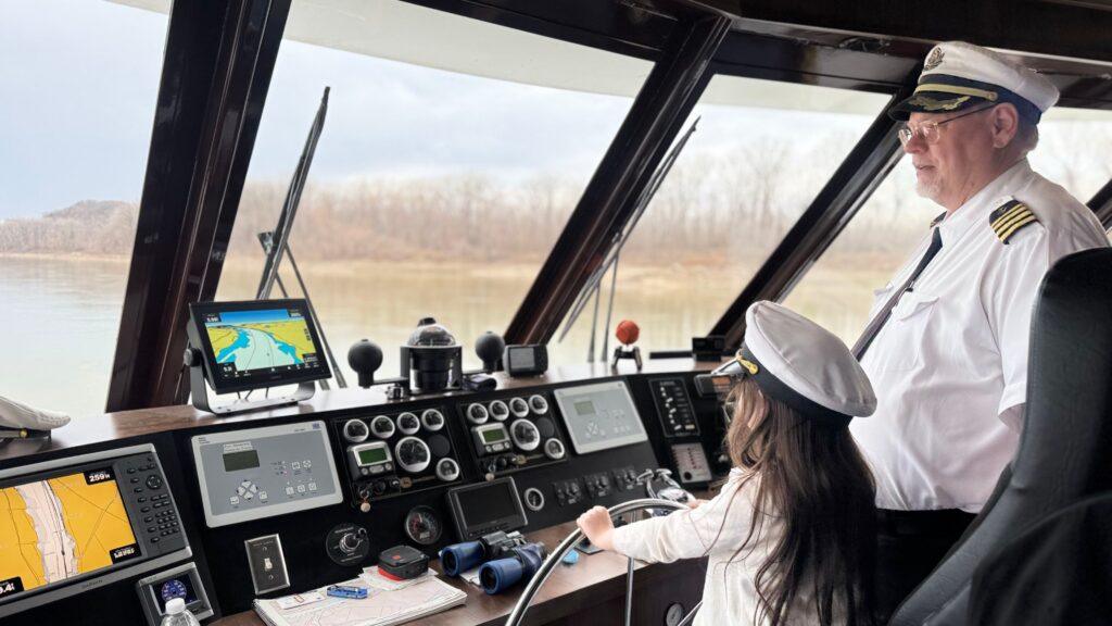 Captain Gary showing our 8-year-old daughter how to pilot The Miss Augusta. Image by Christianne Klein