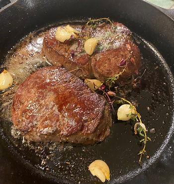 filet mignon in pan with garlic and herbs
