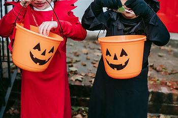 Two trick-or-treaters with candy pails. 